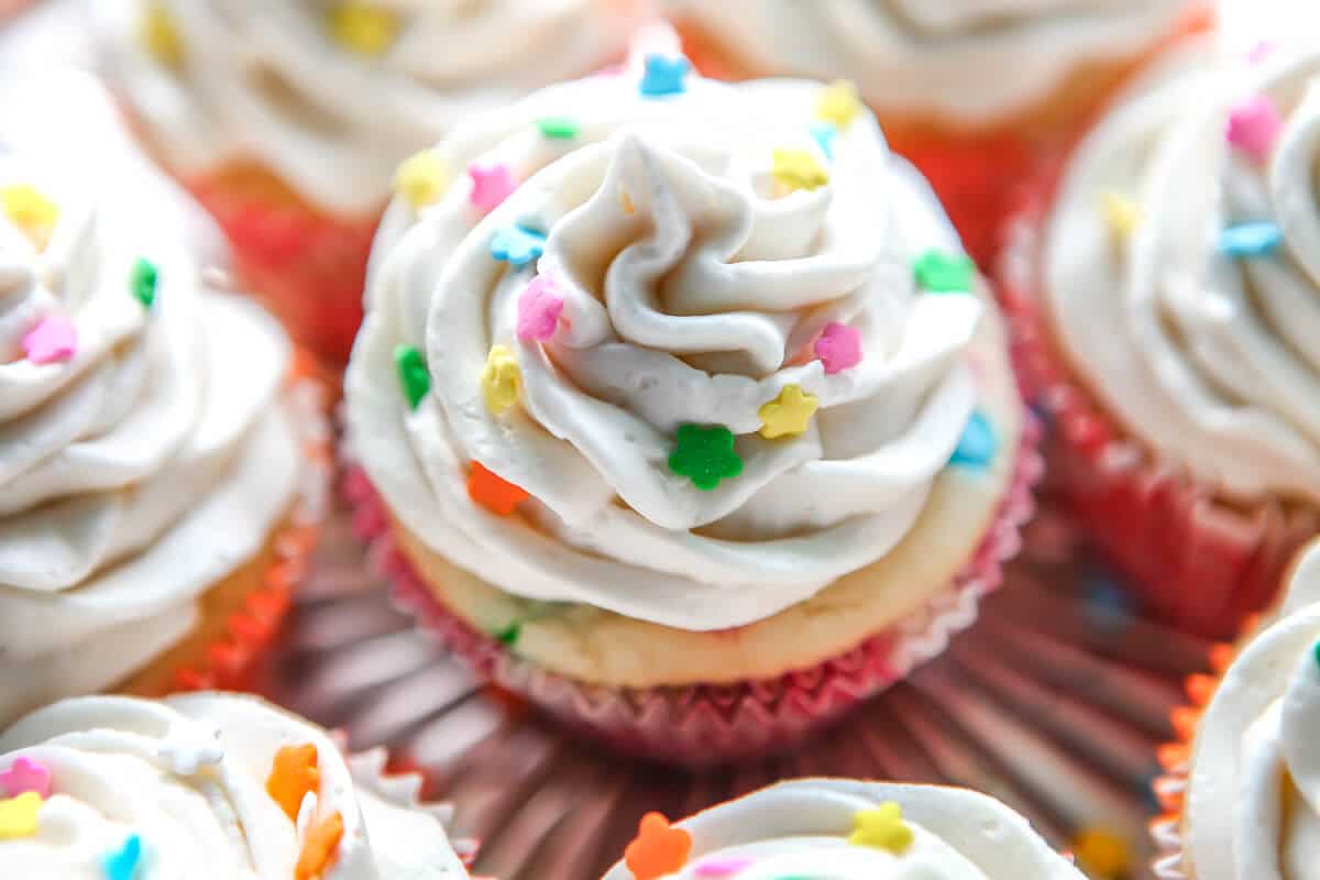 Funfetti vegan cupcakes topped with vanilla vegan frosting and sprinkles.