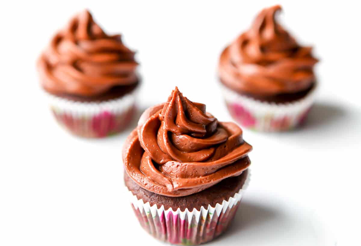Three vegan cupcakes topped with chocolate vegan frosting.