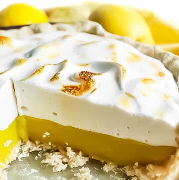 A close up of a slice of a classic vegan lemon meringue pie with aquafaba meringue topping and vegan lemon curd.