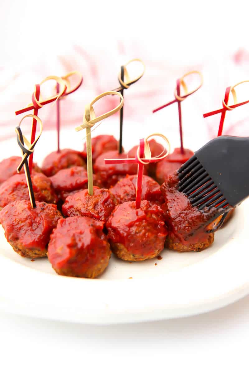 Vegan meatballs being brushed with bbq sauce.