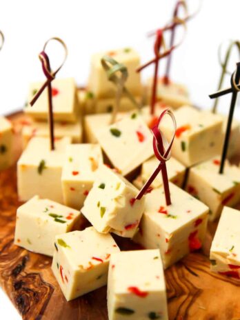 Vegan pepper jack cheese cubes on a cutting board.