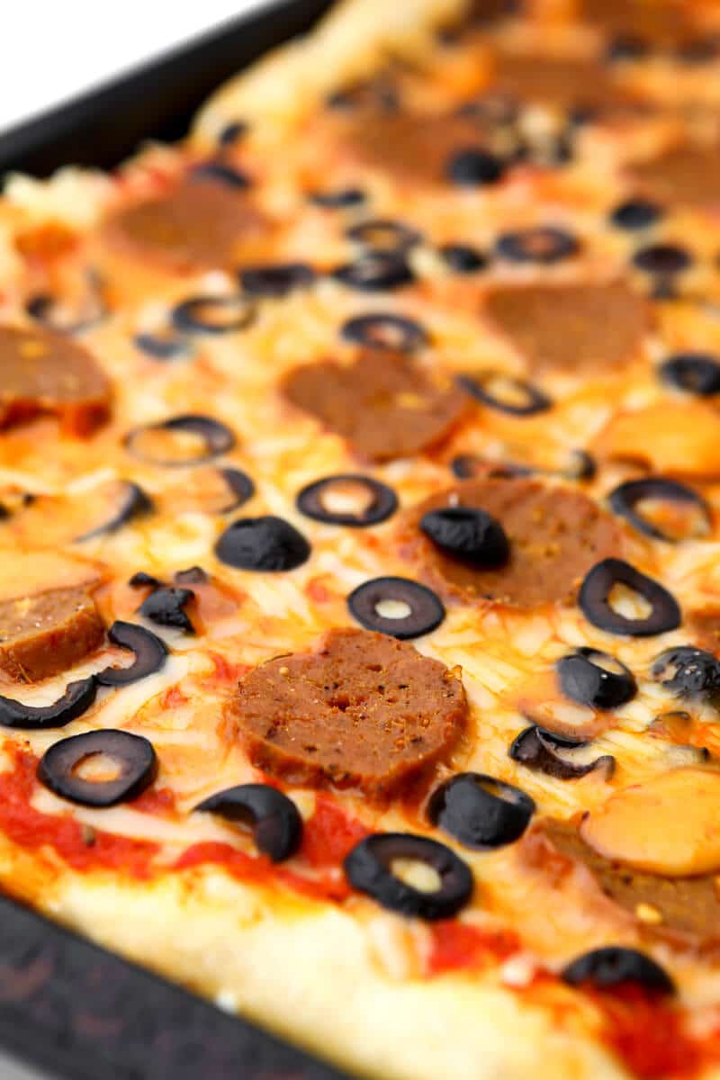 A pizza with vegan pepperoni and black olives.