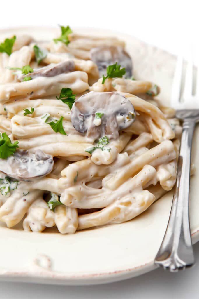 Creamy mushroom pasta sauce served mixed with pasta with a fork on the side.
