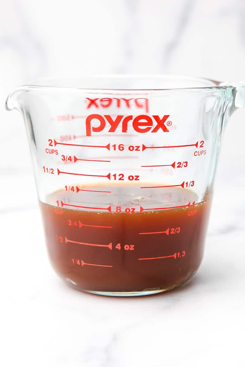 A glass Pyrex measuring cup filled with one cup of the vegan apple liquid sweetener.