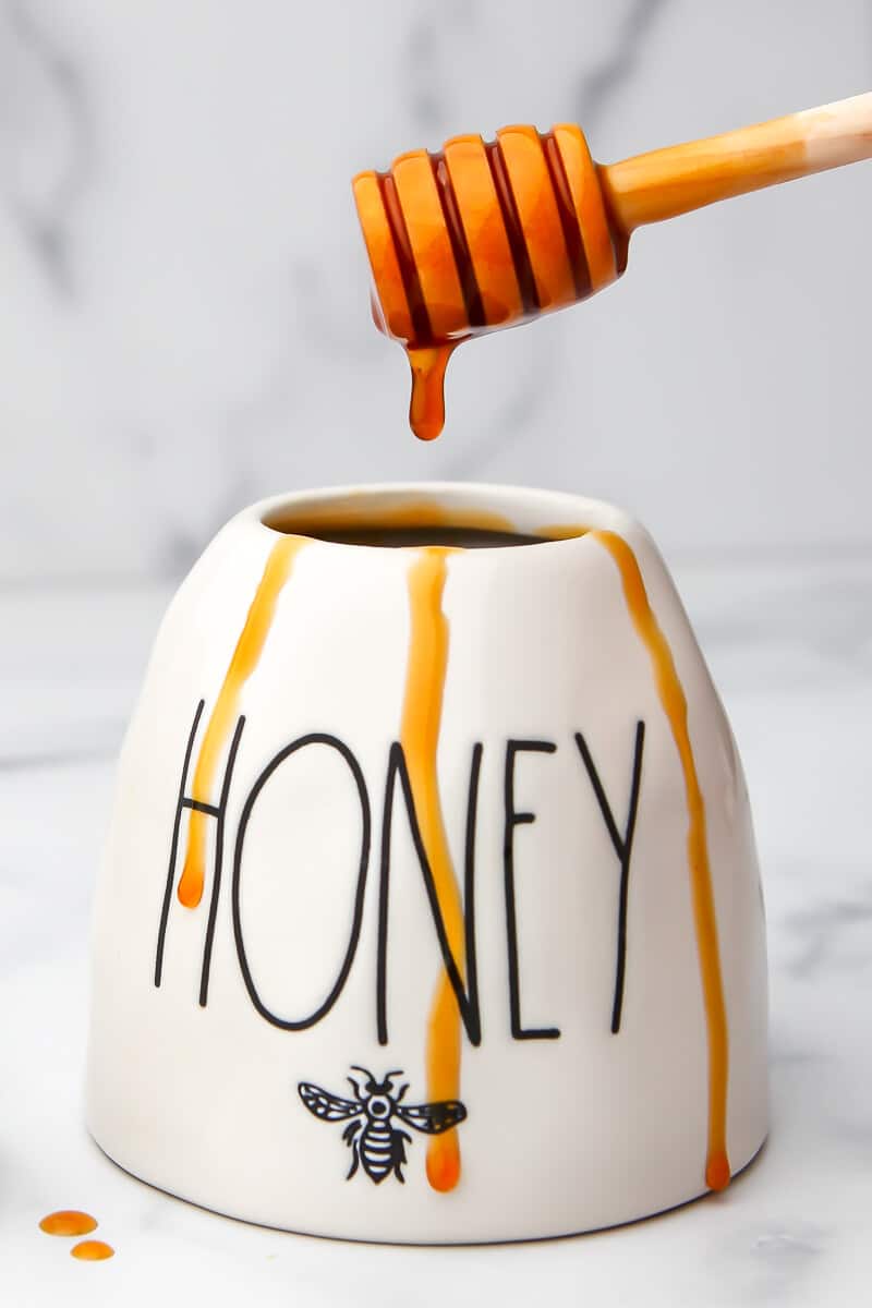 A honey pot with apple honey dripping down the sides.