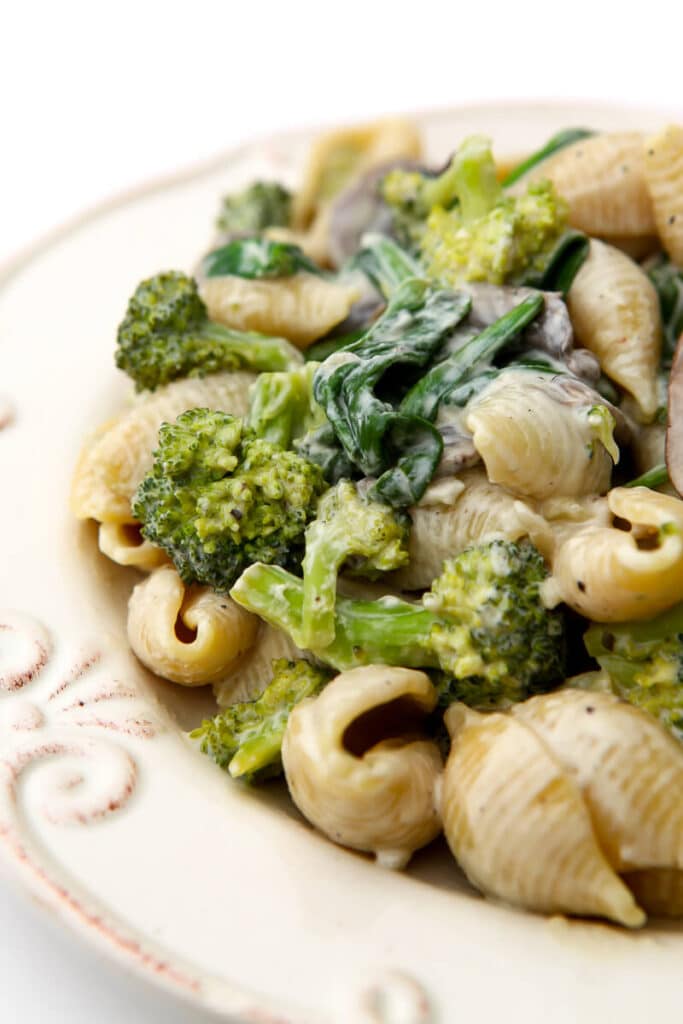 A creamy vegan pasta with mushrooms, broccoli, and spinach.