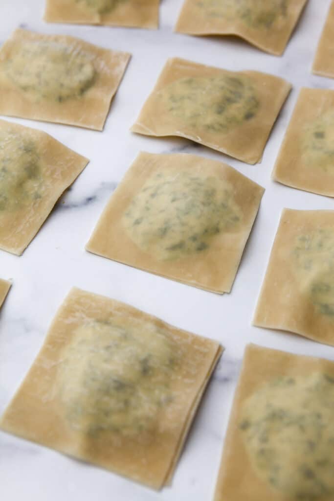 Assembled tofu ravioli on a marble countertop.