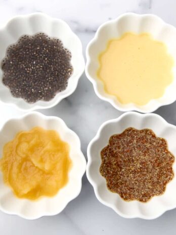 Four small white bowls filled with flax egg, chickpea flour egg, chia seed egg, and apple sauce to replace eggs in baking.
