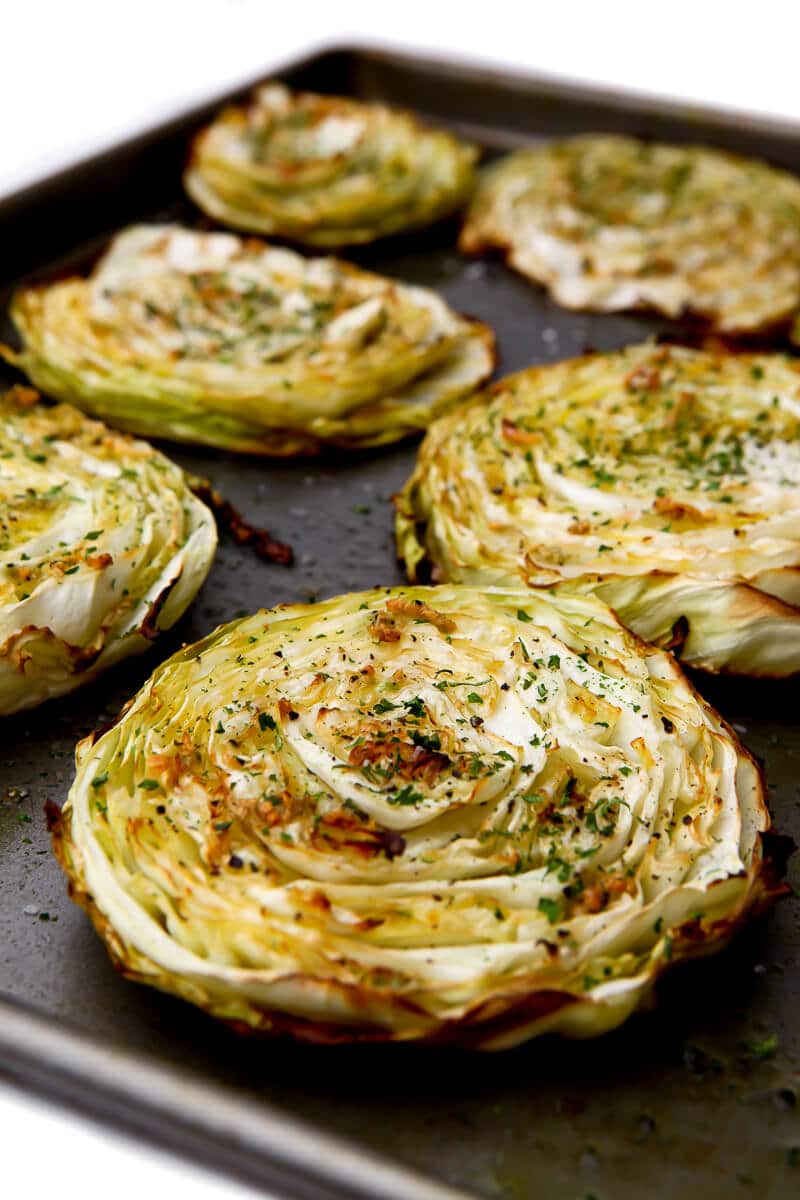 A tray of cabbage slices roasted with garlic and olive oil drizzled on top before baking.