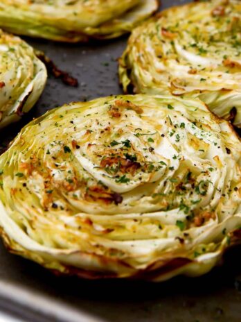 A close up of a cabbage steak on a cookie sheet after roasting in the oven.