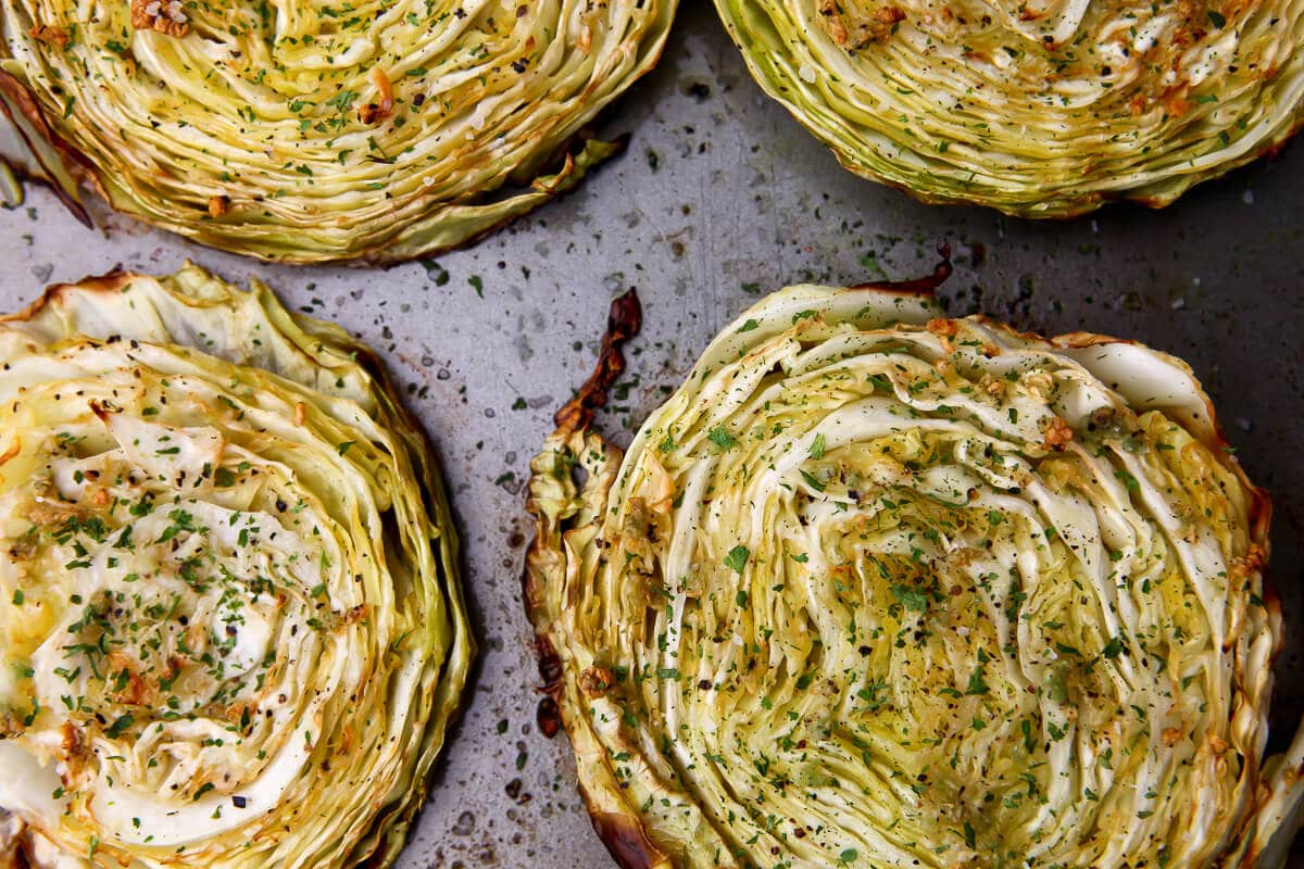 A top view of roasted cabbage steaks with garlic and parsley.
