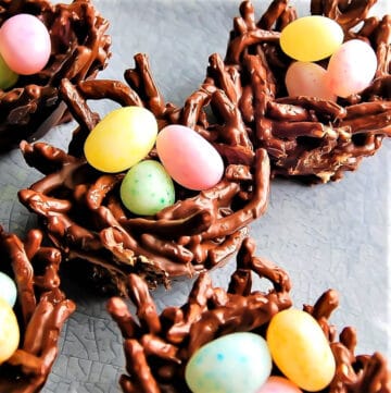 Vegan bird's nest cookies filled with jelly beans on a blue plate.