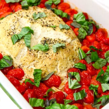 A block of tofu feta baked with olive oil and cherry tomatoes and topped with basil.