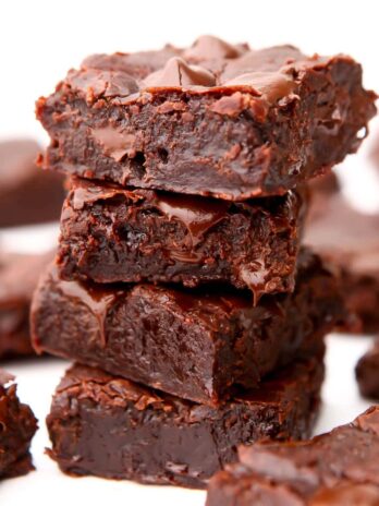 A stack of fudgy vegan brownies with more brownies around it.