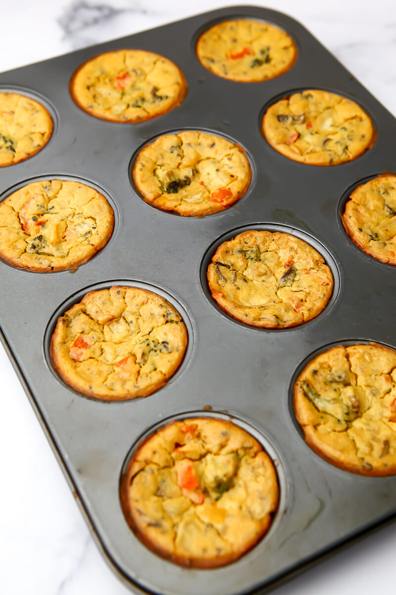 Cooked vegan egg muffins with cracks on the tops in the tin after coming out of the oven.
