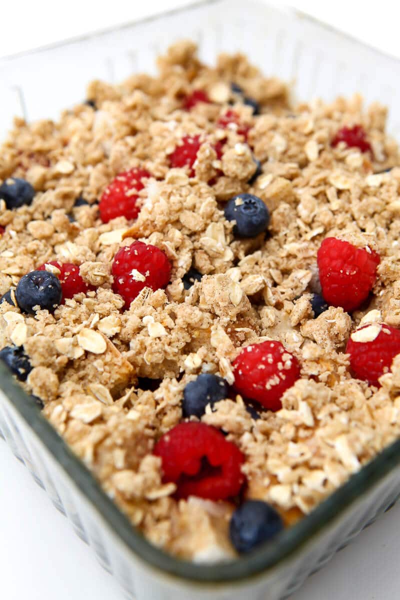 A vegan French toast casserole with berries and a crumble crust before baking.