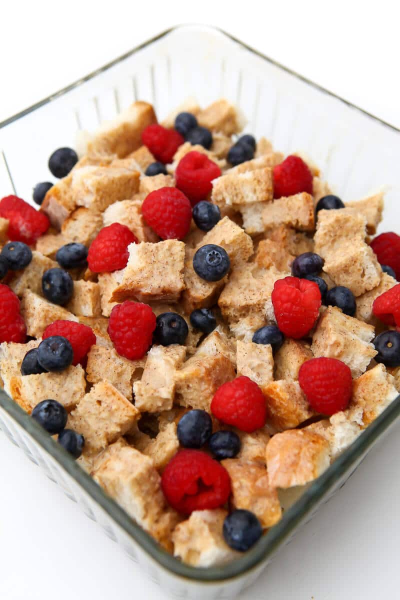 A casserole filled with vegan French toast cubes and topped with berries.