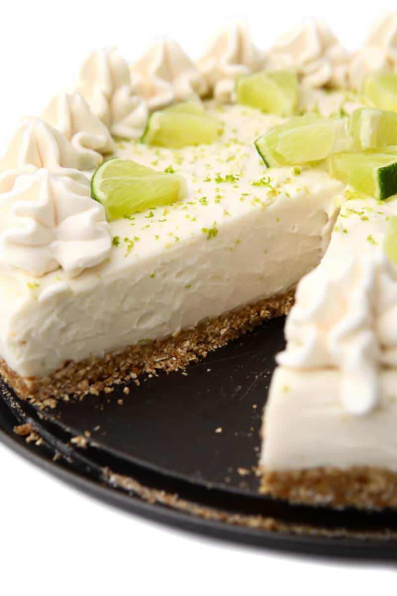 A vegan key lime pie with a slice cut out of it.