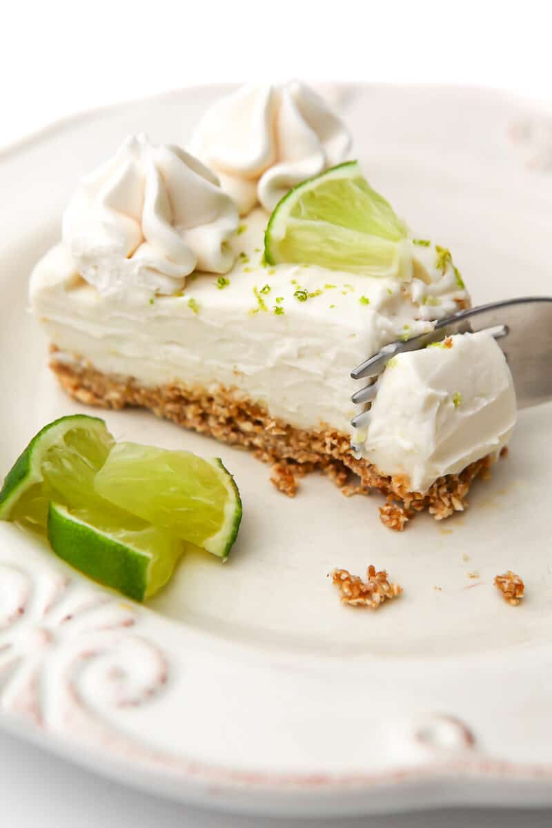 A slice of a vegan key lime cheesecake with a fork cutting a bite off of it.