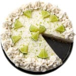 A top view of a vegan key lime pie with whipped cream and lime wedges decorating the top.