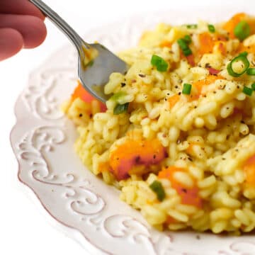 A close up of vegan squash risotto with a fork taking some out of it.