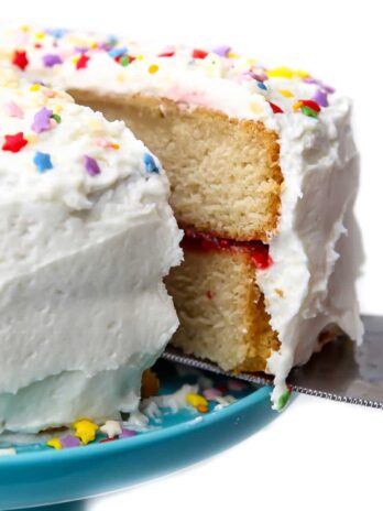 A slice being taken out of a vegan vanilla cake with raspberry filling.