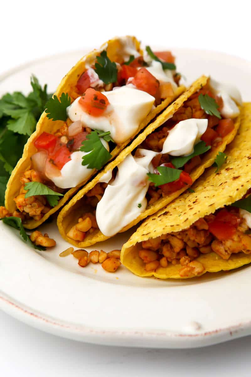 A plate filled with tempeh tacos with salsa and vegan sour cream.