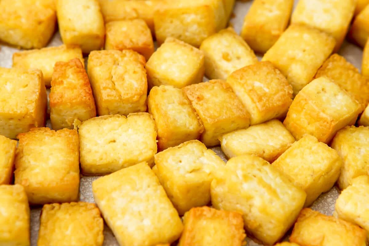 A close up of pan-fried tofu in a white skillet.