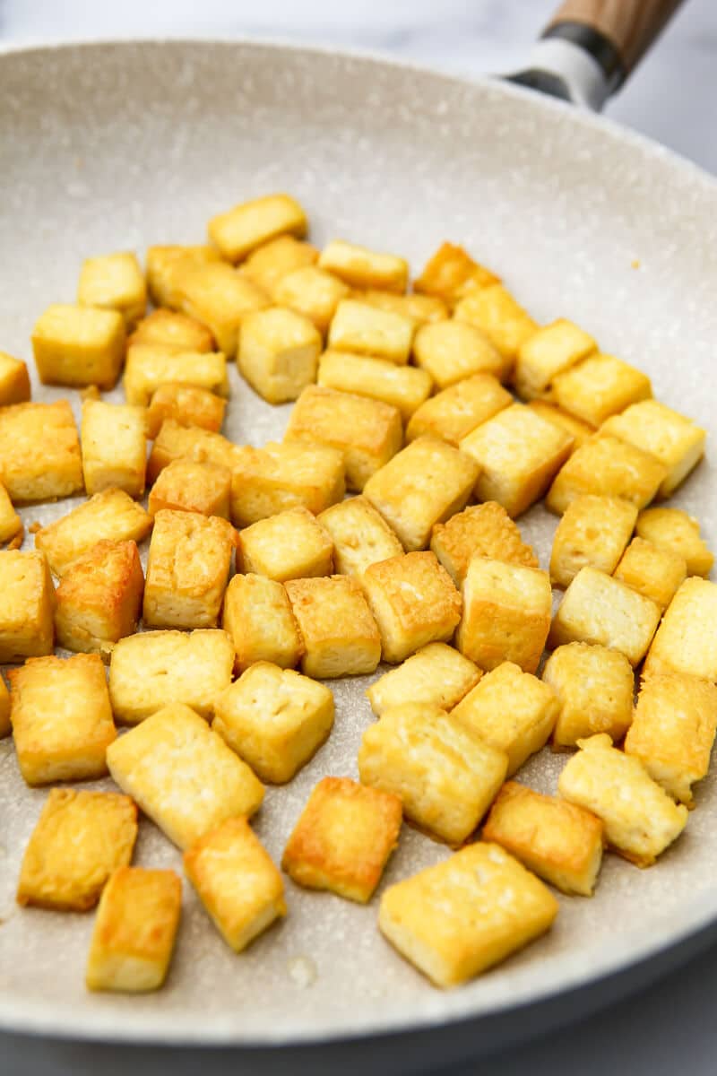 A frying pan filled with cubes of pan-fried tofu.