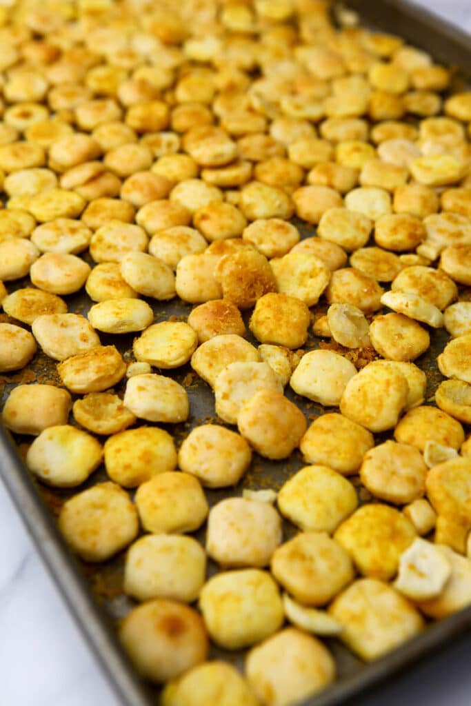 Oyster crackers with oil, nutritional yeast, and salt on a cookie sheet to make vegan goldfish style crackers.