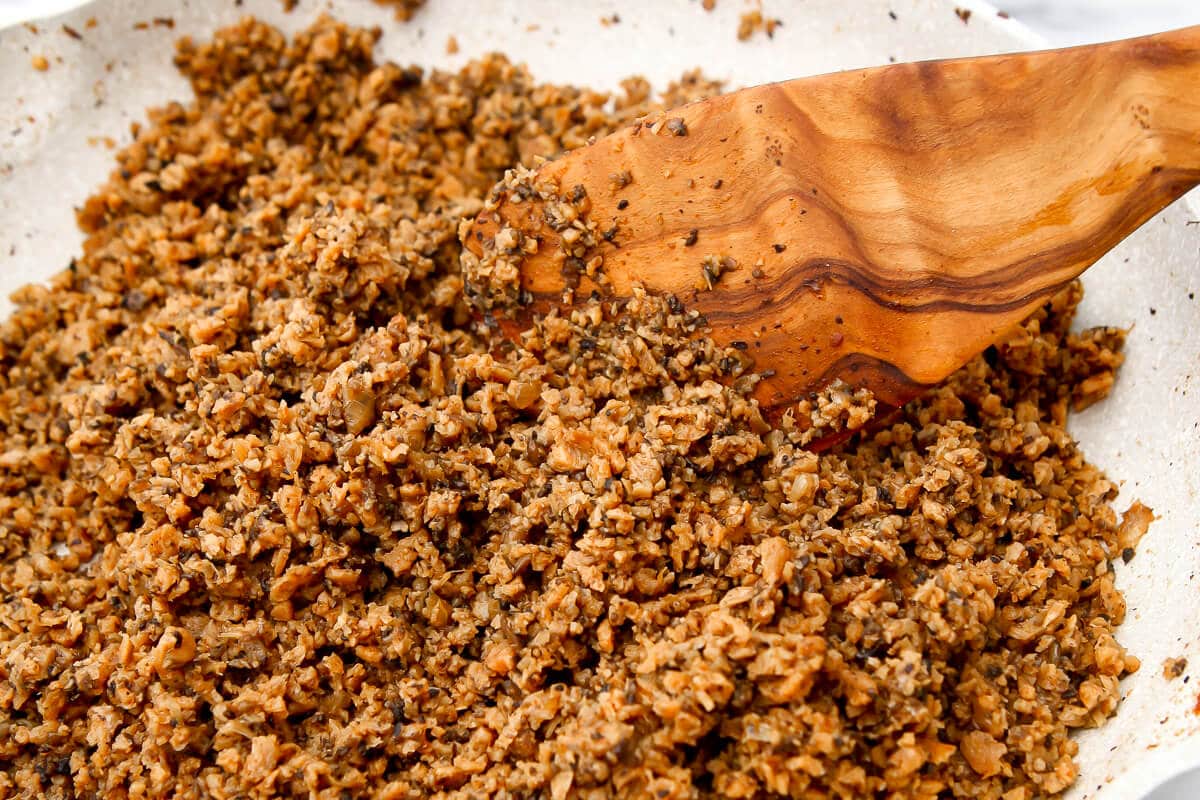 A close up of meatless crumbles being stirred in a skillet.