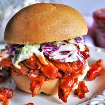 A gluten free vegan pulled pork sandwich made with soy curls and colorful vegan coleslaw.