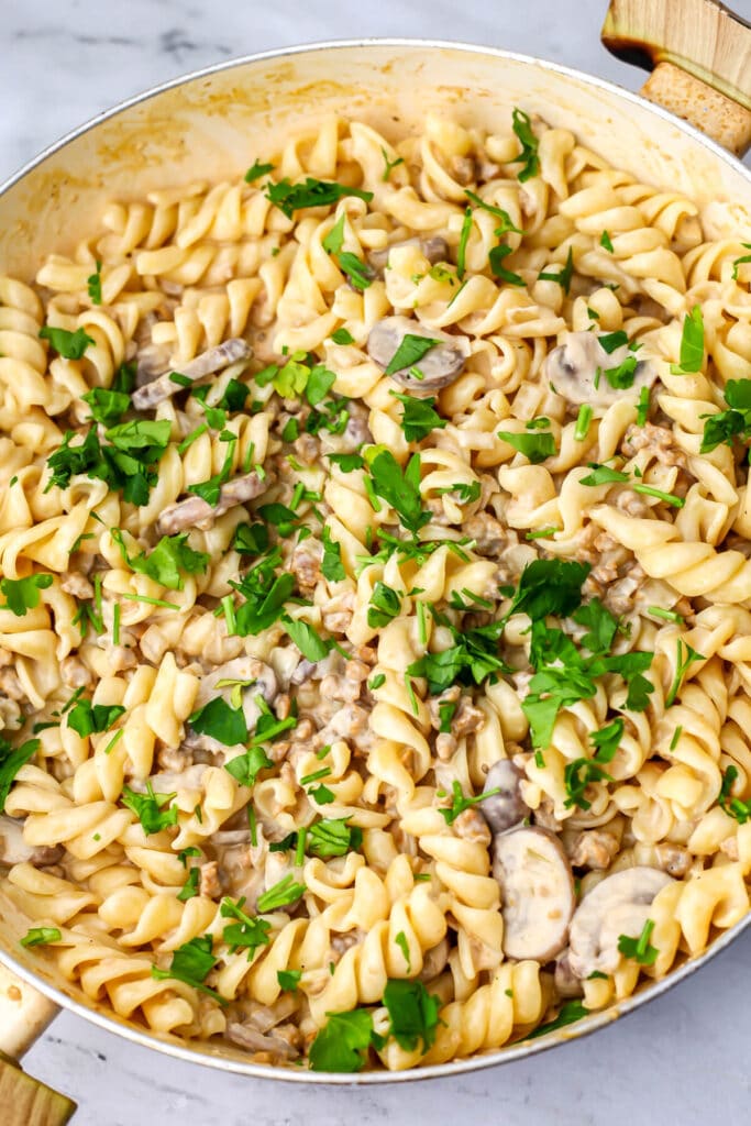 A top view of a large pan filled with vegan stroganoff topped with parsley.