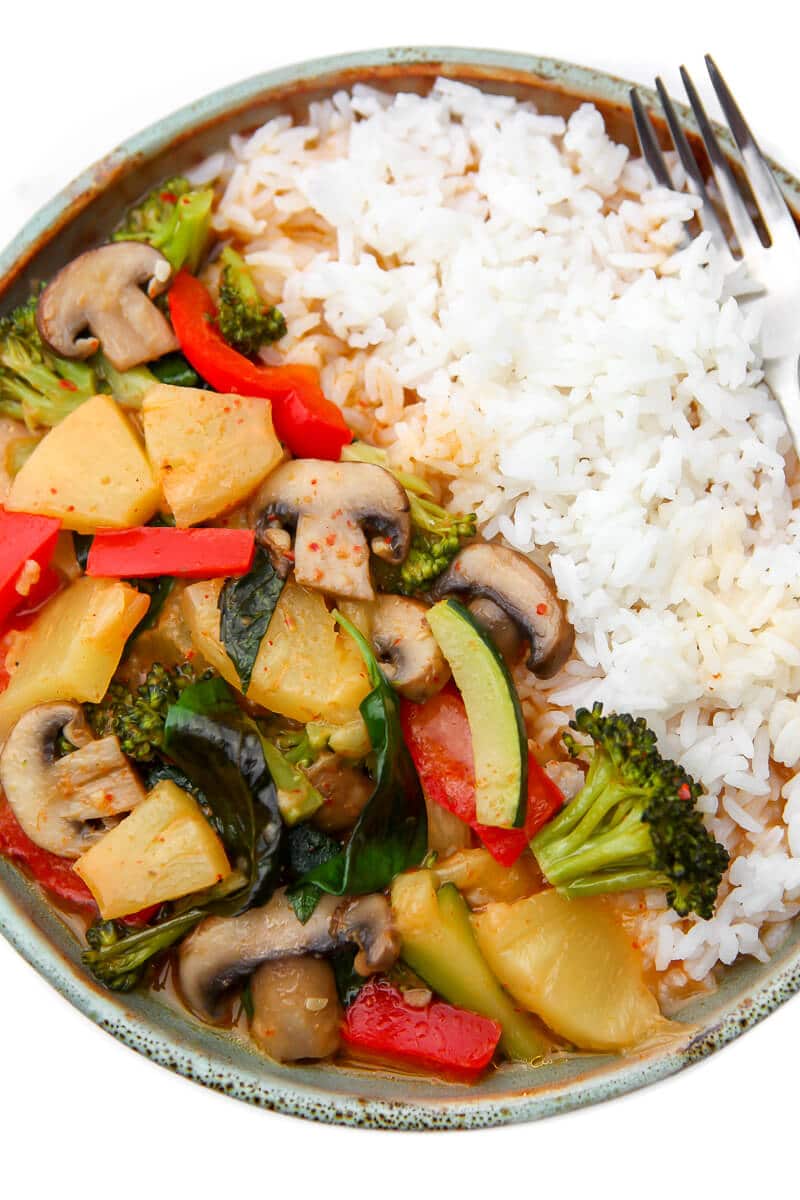 A top view of a plate filled with rice and vegan Thai red curry with veggies and pineapple.
