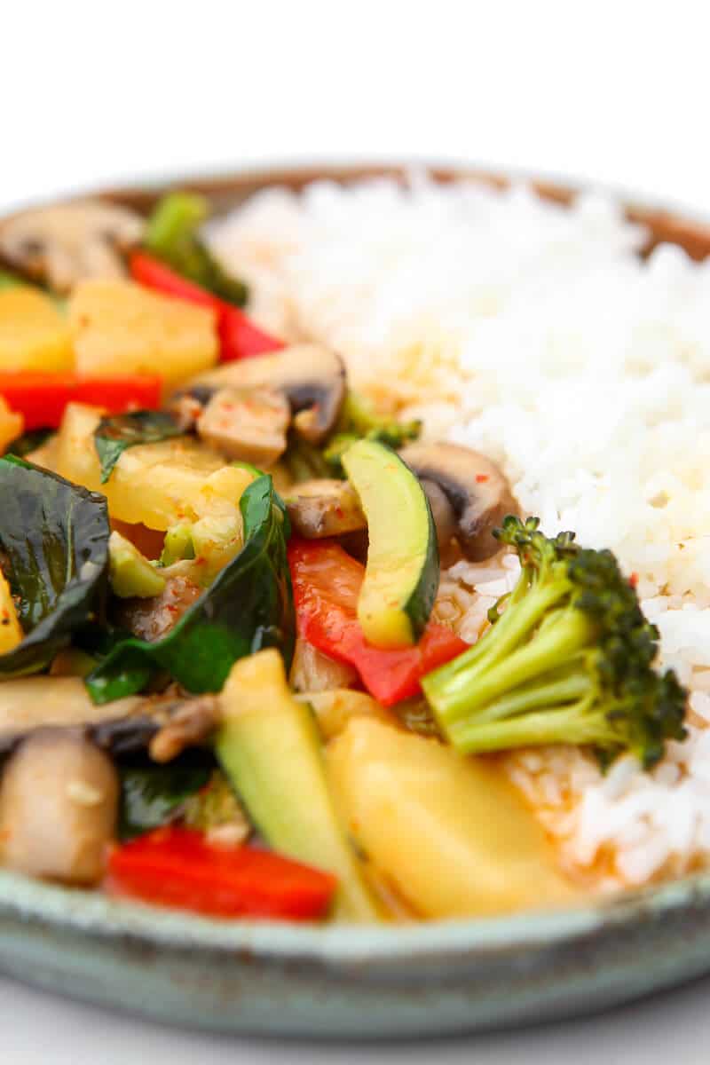 Red Thai curry sauce with veggies on a plate with rice.