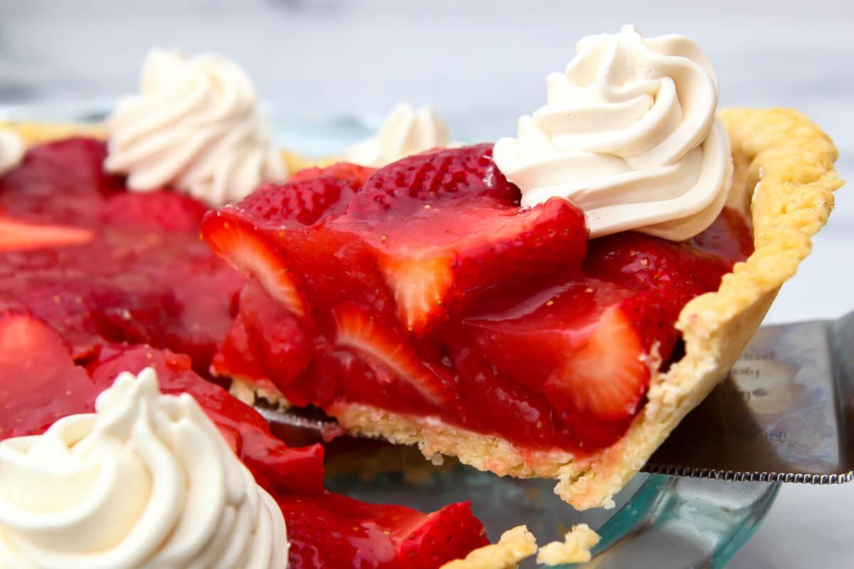 A slice being taken out of a vegan strawberry pie.
