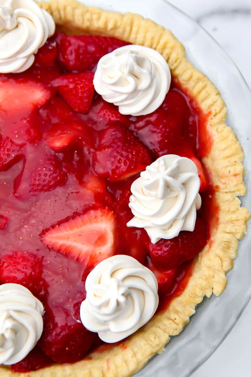 A top view of a vegan strawberry pie with whipped cream on top.