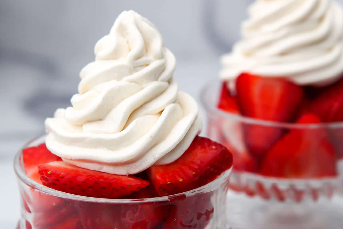 Vegan whipped cream on top of strawberries.