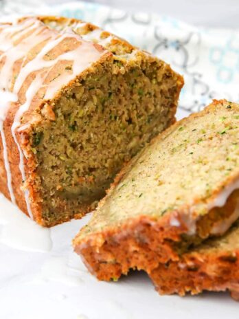 A loaf of slice vegan zucchini bread with lemon glaze drizzled on top.