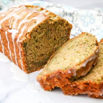A loaf of slice vegan zucchini bread with lemon glaze drizzled on top.