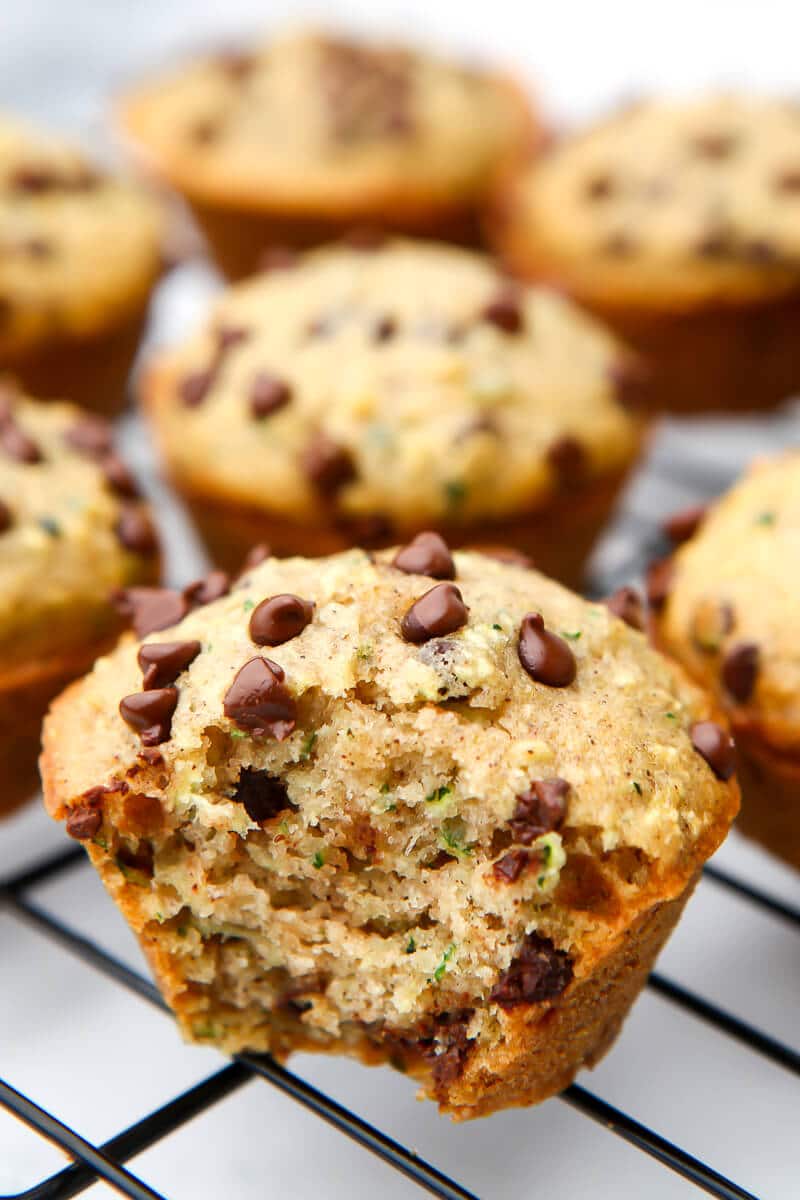 Chocolate chip zucchini muffins on a cooling wire rack with a bit taken out of a muffin.