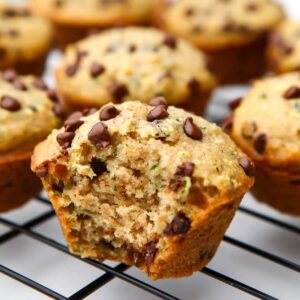 A close up of a vegan zucchini muffin with a bite taken out of it.
