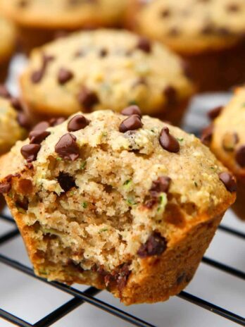 A close up of a vegan zucchini muffin with a bite taken out of it.