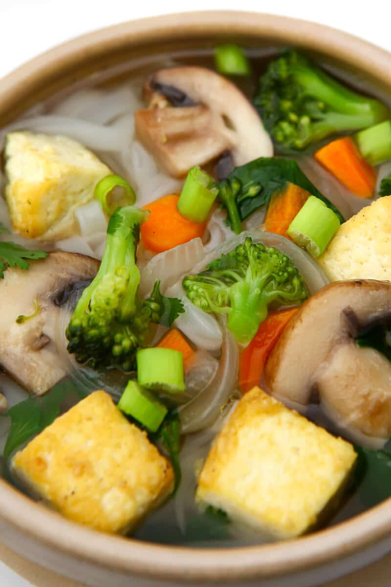 A top view of a bowl of vegan Pho soup with tofu, mushrooms, and broccoli.