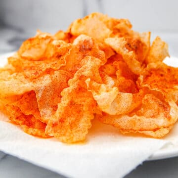 A pile of vegan pork rinds made with fried rice paper on a white plate.