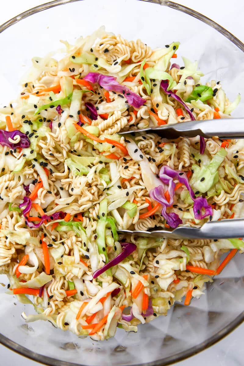 A top view of a vegan ramen noodle salad with tong in it.