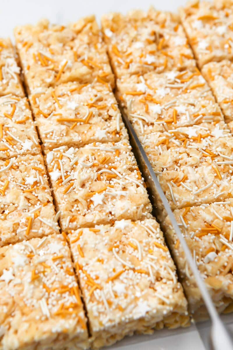 A knife cutting rice krispie treats into squares.