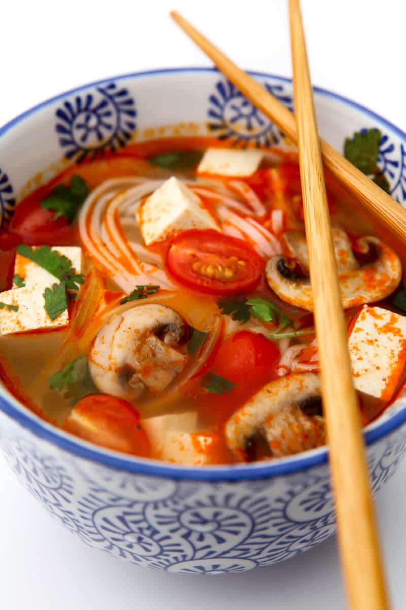A blue bowl filled with spicy vegetable tom yum soup.