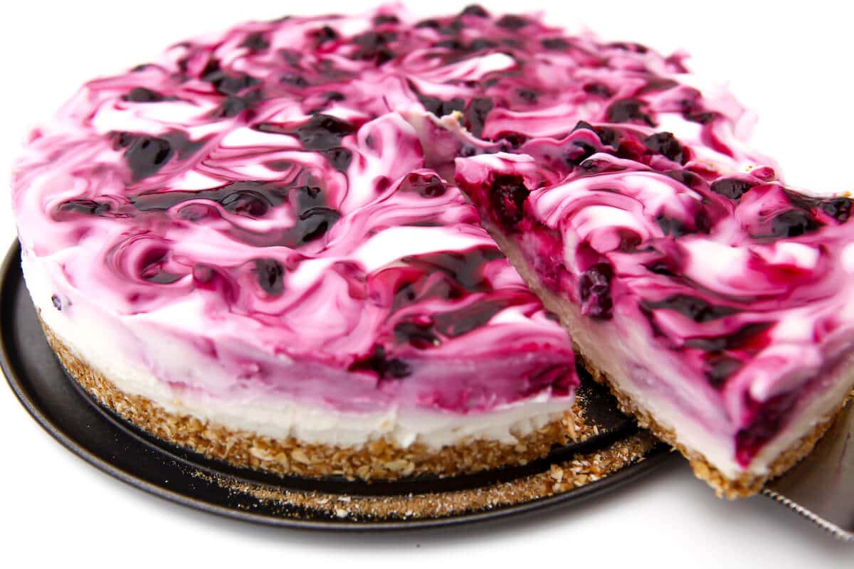 Someone taking a slice of a dairy-free blueberry cheesecake.