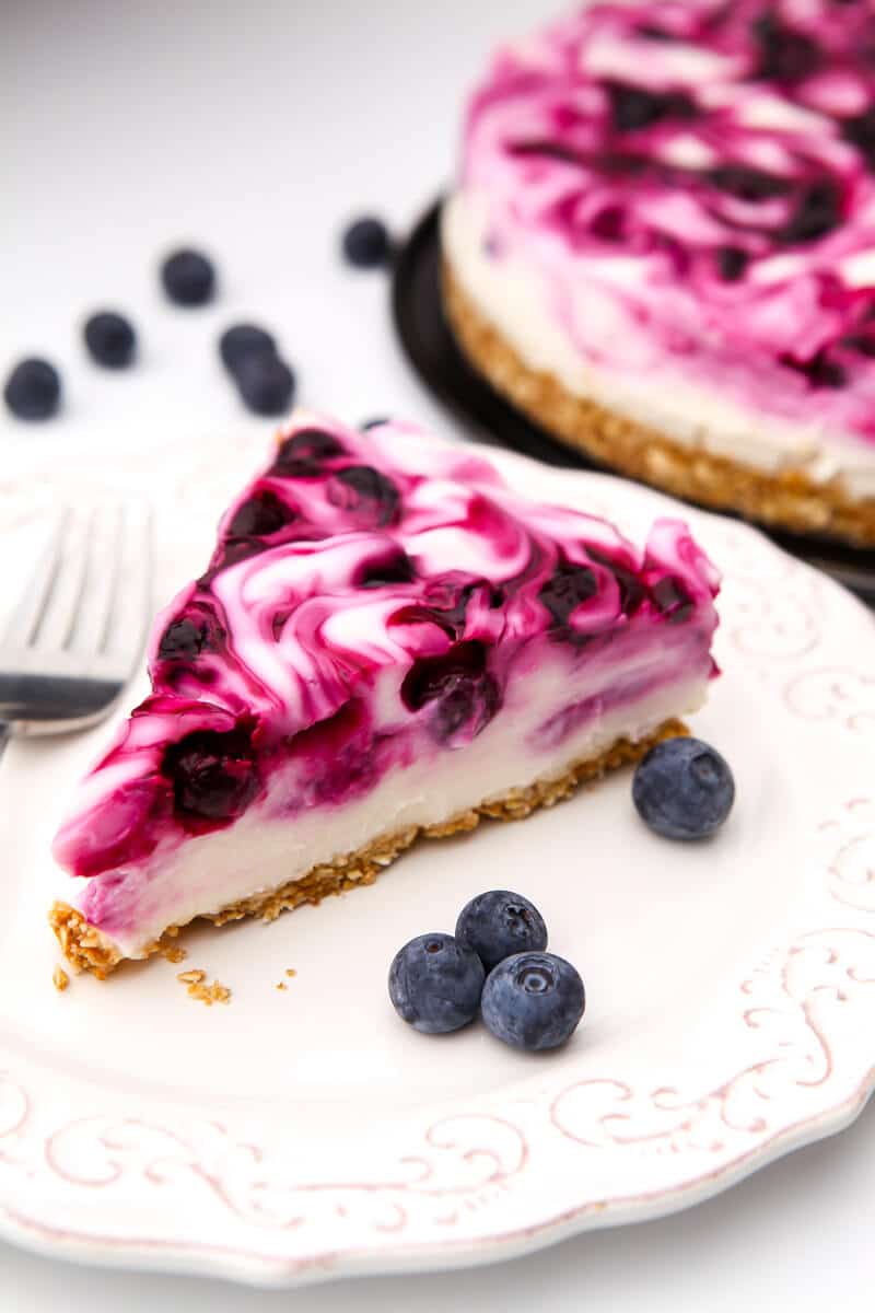 A slice of a vegan cheesecake with blueberries swirled into it.